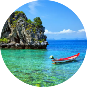 Traditional wooden boat floating on crystal-clear turquoise waters beside rocky islands in the Andaman Islands.
